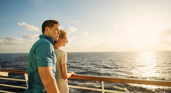 Paar im Kreuzfahrt Urlaub mit Sonnenuntergang im Hintergrund