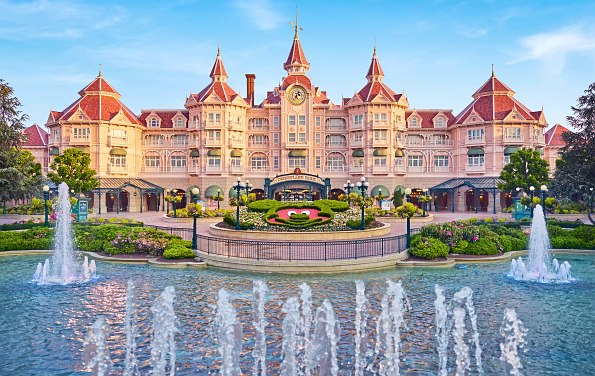 Hotel im Disneyland Paris mit Türmen und Spitzen und davor einem Brunnen