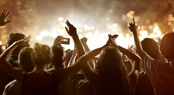 Publikum von hinten mit Blick auf die Bühne und Händen in der Luft 