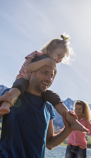 Familie mit zwei Kindern stehen am Ufer eines Sees.