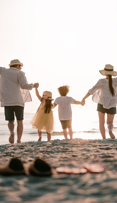 Kleines blondes Mädchen steht vor dem geöffneten Kofferraum mit blauem und grünen Koffer und streckt sich