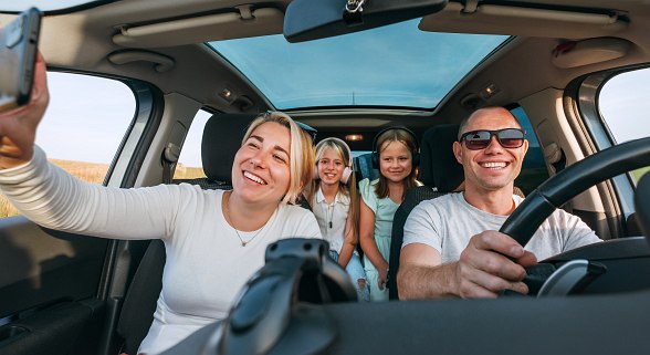 Familie sitzt im Auto und genießt einen günstigen Urlaub 