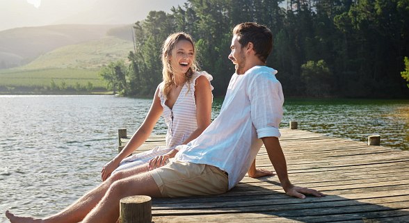 Paar sitzt am Steg und genießt ihre Zeit im Urlaub