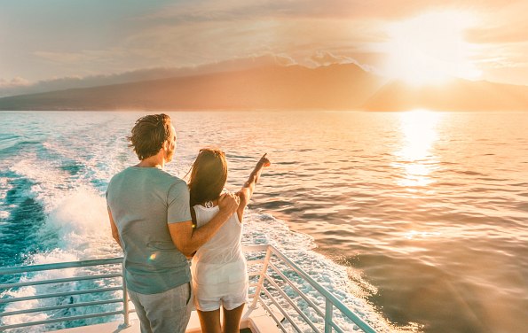 Paar an Deck eines Kreuzfahrtschiffes, Meer und Sonnenuntergang im Hintergrund
