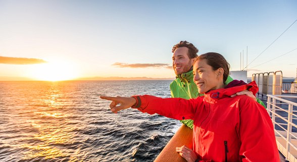 Paar ist auf einer Kreuzfahrt und bestaunt den Ausblick auf dem Meer