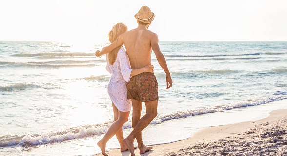 Paar geht am Strand in der Nähe des Hotels spazieren und ist sehr sommerliche angezogen