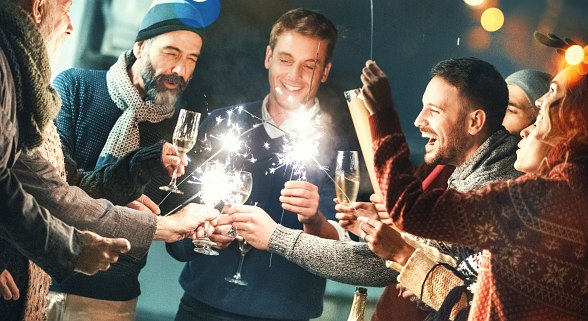 Junge Leute feiern Silvester mit Sektgläsern und Sprühkerzen