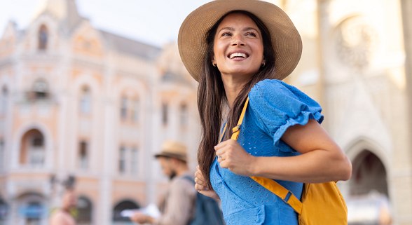Junge Frau mit Hut und Rucksack auf Städtetour