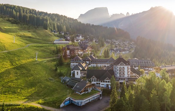 Hotel von außen und Berge und Wiesen im Hintergrund mit schönem Lichteinfall