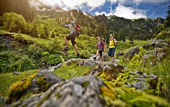 Drei Wanderer in schöner Natur mit Felsen und Wald im Hintergrund