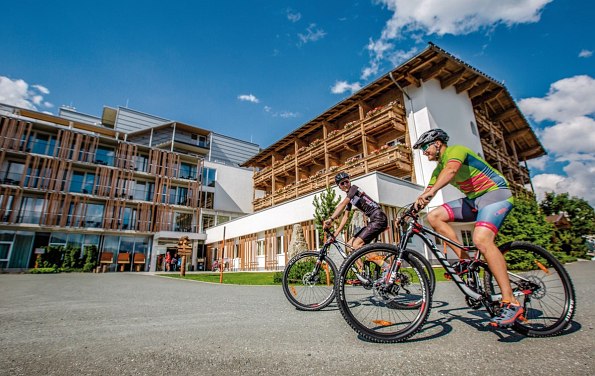 Zwei Radfahrer vor dem Alpenhotel Kaiserfels mit blauem Himmel im Hintergrund