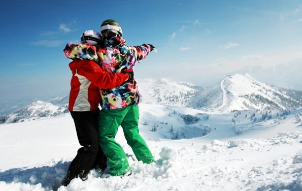 Zwei Kinder im Skianzug im Schnee mit Blick auf die verschneiten Berge
