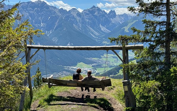 Paar in einer Holzschaukel mit Blick auf die Berge im Hintergrund