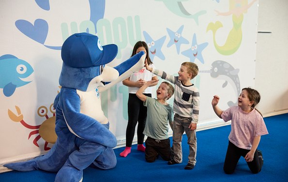 Delphinmaskottchen klatscht mit ein paar Kindern ab